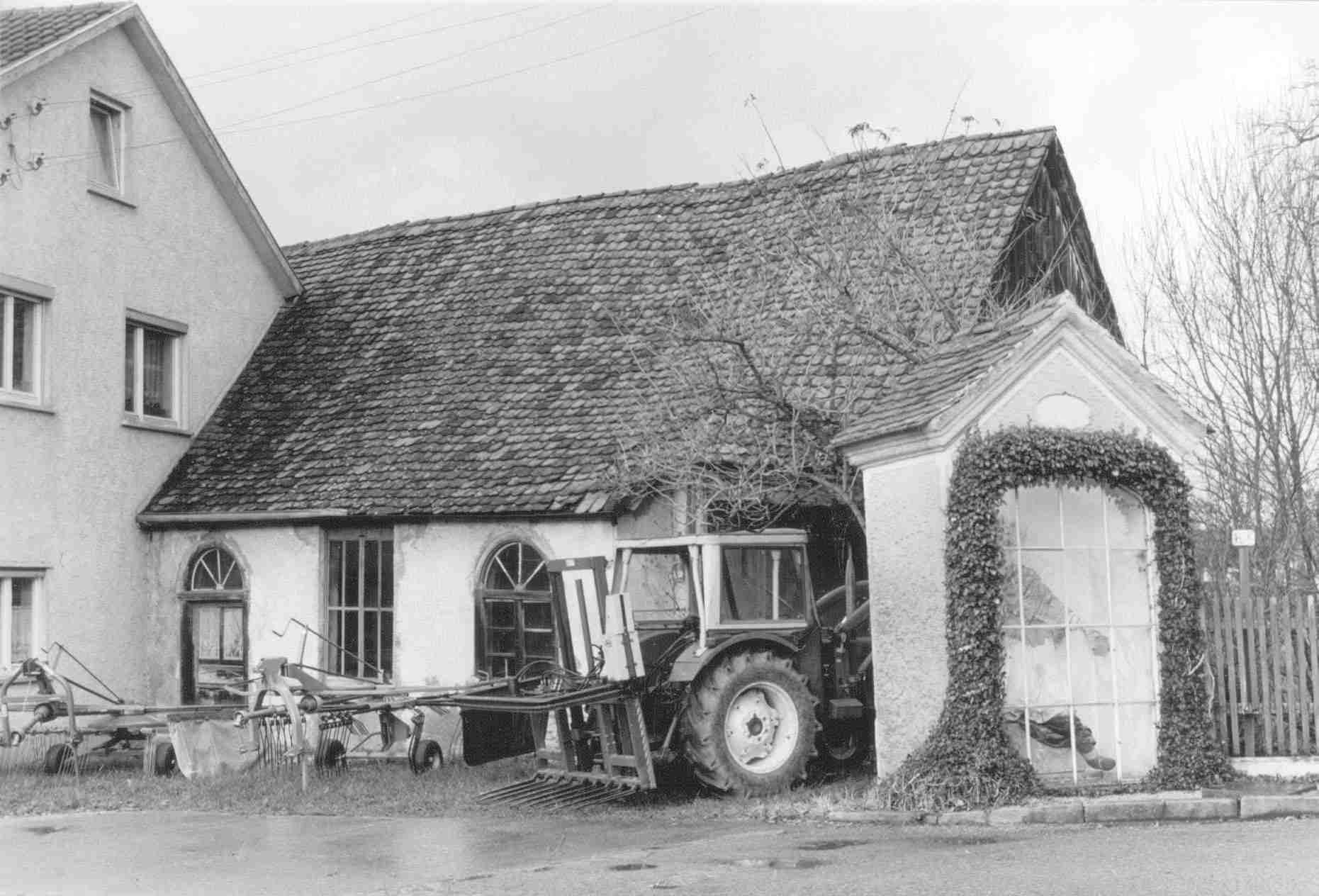 Die ehemalige Ölmühle und Dosersche Werkstatt vor dem Abbau durch das Schwäbische Bauernhofmuseum Illerbeuren im Jahr 1987. Die Nepomuk-Kapelle im Bild rechts vorne ließ Johann Nepomuk Doser (I) errichten.